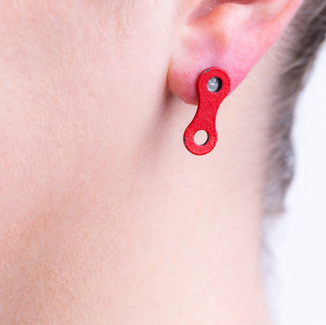Model showcasing Lone Rider red bike chain stud earrings handmade from recycled bicycle parts.